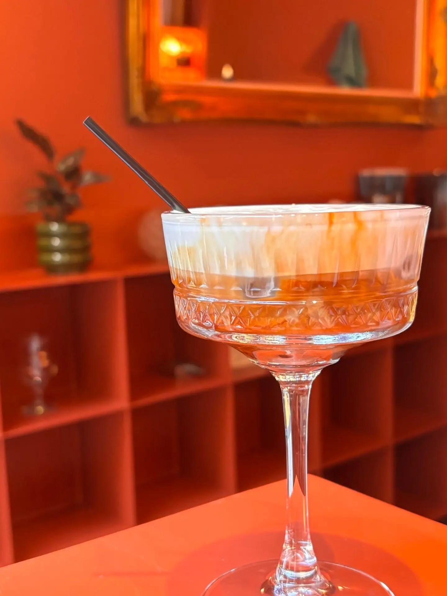 A drink in a tall glass against the orange shelves